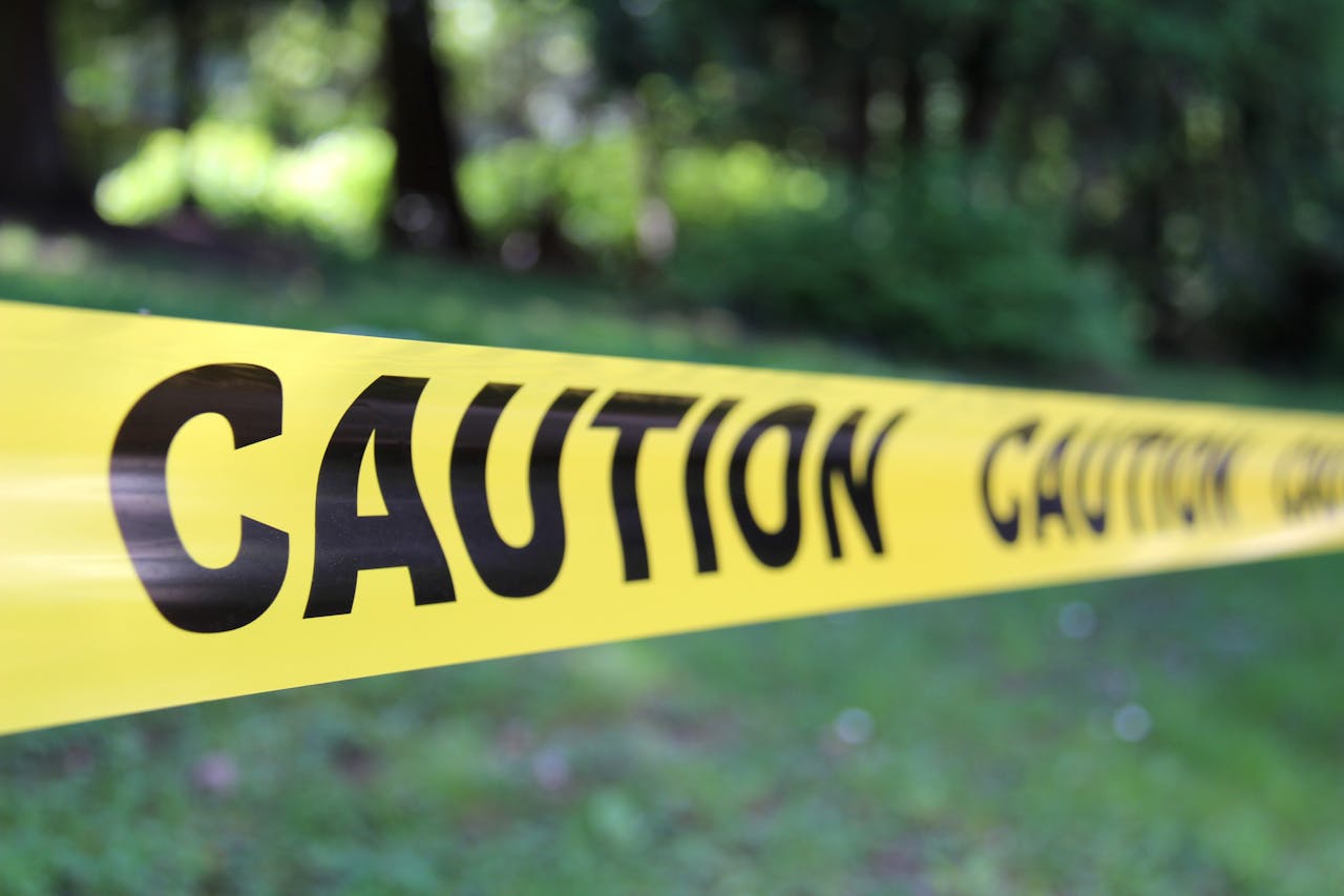 Close-up of yellow caution tape in a forest setting indicating danger or restriction.